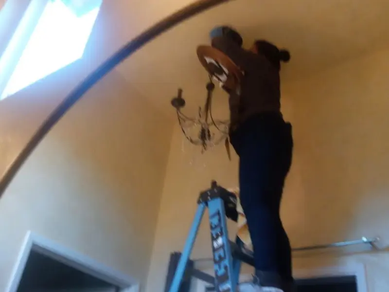 Electrician installing a chandelier in a Chamberlayne residence